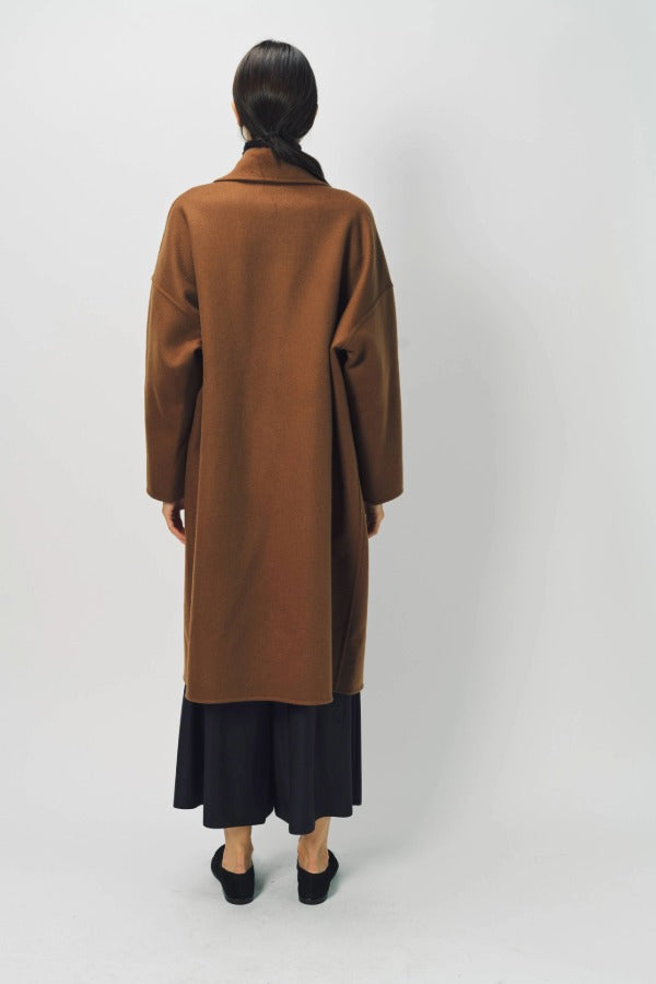 Back view of palissandro oversized coat on model wearing navy pants and loafers, against a white background.