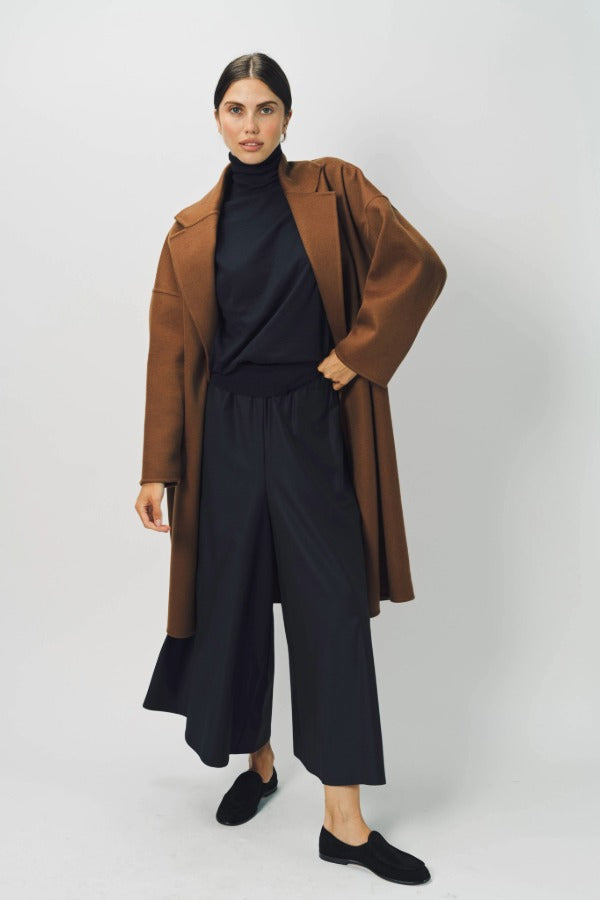 Alternate front view of palissandro oversized coat on model wearing navy turtleneck, pants and loafers, against a white background.