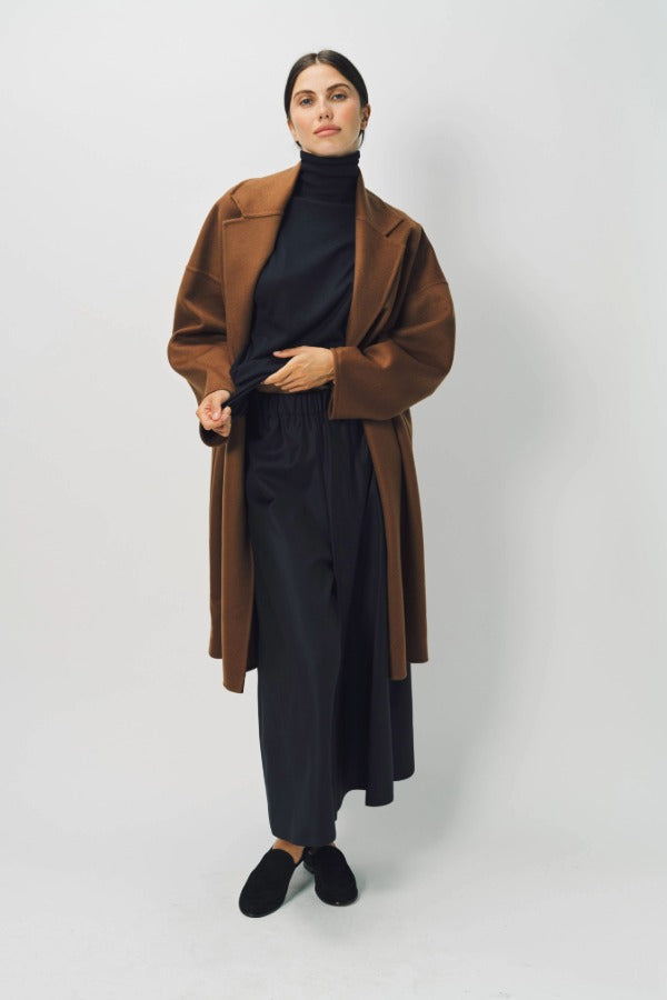 Alternate front view of palissandro oversized coat on model wearing navy turtleneck, pants, and loafers, against a white background.