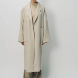 Front view of oatmeal cashmere patch pocket long coat on model wearing beige pants and oatmeal sweater, against a white background.