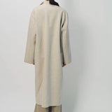 Back view of oatmeal cashmere patch pocket long coat on model wearing beige pants , against a white background.