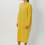 Side view of sunray iconic cashmere dress on model wearing loafers, against a white background.