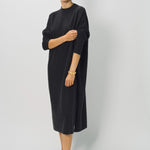 Side view of black wood iconic cashmere dress on model wearing loafers, against a white background.