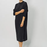 Side view of black wood iconic cashmere dress on model wearing loafers, against a white background.