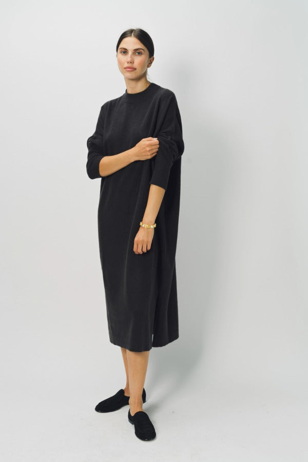 Side view of black wood iconic cashmere dress on model wearing loafers, against a white background.