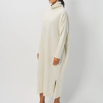 Side view of bone iconic cashmere t-neck dress on model wearing loafers, against a white background.