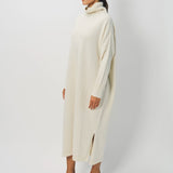 Side view of bone iconic cashmere t-neck dress on model wearing loafers, against a white background.