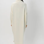 Back view of bone iconic cashmere t-neck dress on model wearing loafers, against a white background.