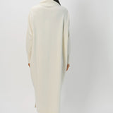 Back view of bone iconic cashmere t-neck dress on model wearing loafers, against a white background.
