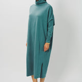 Side view of norfolk blue iconic cashmere t-neck dress on model wearing loafers, against a white background.