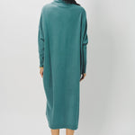 Back view of norfolk blue iconic cashmere t-neck dress on model wearing loafers, against a white background.