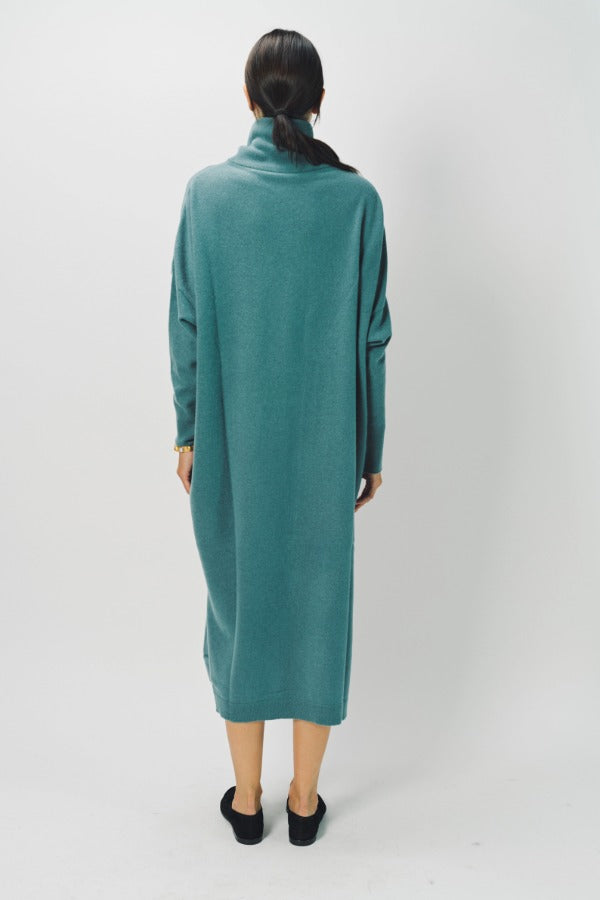 Back view of norfolk blue iconic cashmere t-neck dress on model wearing loafers, against a white background.