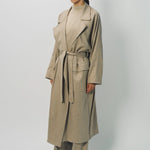 Side view of sand light cashmere trench coat on model wearing sand pants and sweater, against a white background.