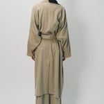 Back view of sand light cashmere trench coat on model wearing sand pants, against a white background.