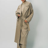 Alternate front view of sand light cashmere trench coat on model wearing sand pants and sweater, against a white background.