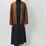 Front view of palissandro oversized coat on model wearing black top, pants and loafers, against a white background.