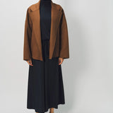 Front view of palissandro oversized coat on model wearing black top, pants and loafers, against a white background.