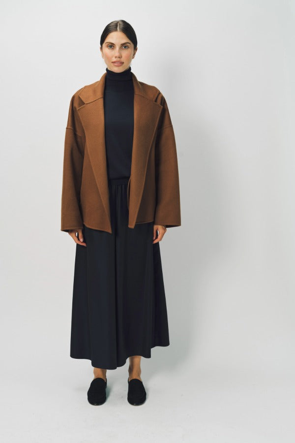 Front view of palissandro oversized coat on model wearing black top, pants and loafers, against a white background.