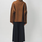 Back view of palissandro oversized coat on model wearing black pants and loafers, against a white background.