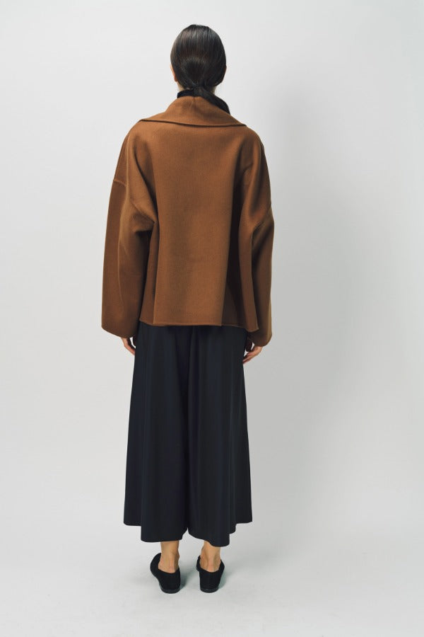 Back view of palissandro oversized coat on model wearing black pants and loafers, against a white background.