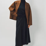 Alternate front view of palissandro oversized coat on model wearing black top, pants and loafers, against a white background.