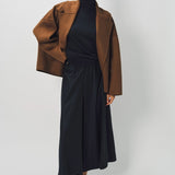 Alternate front view of palissandro oversized coat on model wearing black top, pants and loafers, against a white background.
