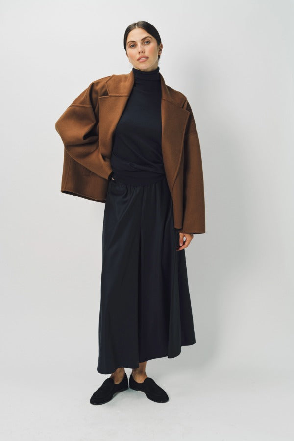 Alternate front view of palissandro oversized coat on model wearing black top, pants and loafers, against a white background.