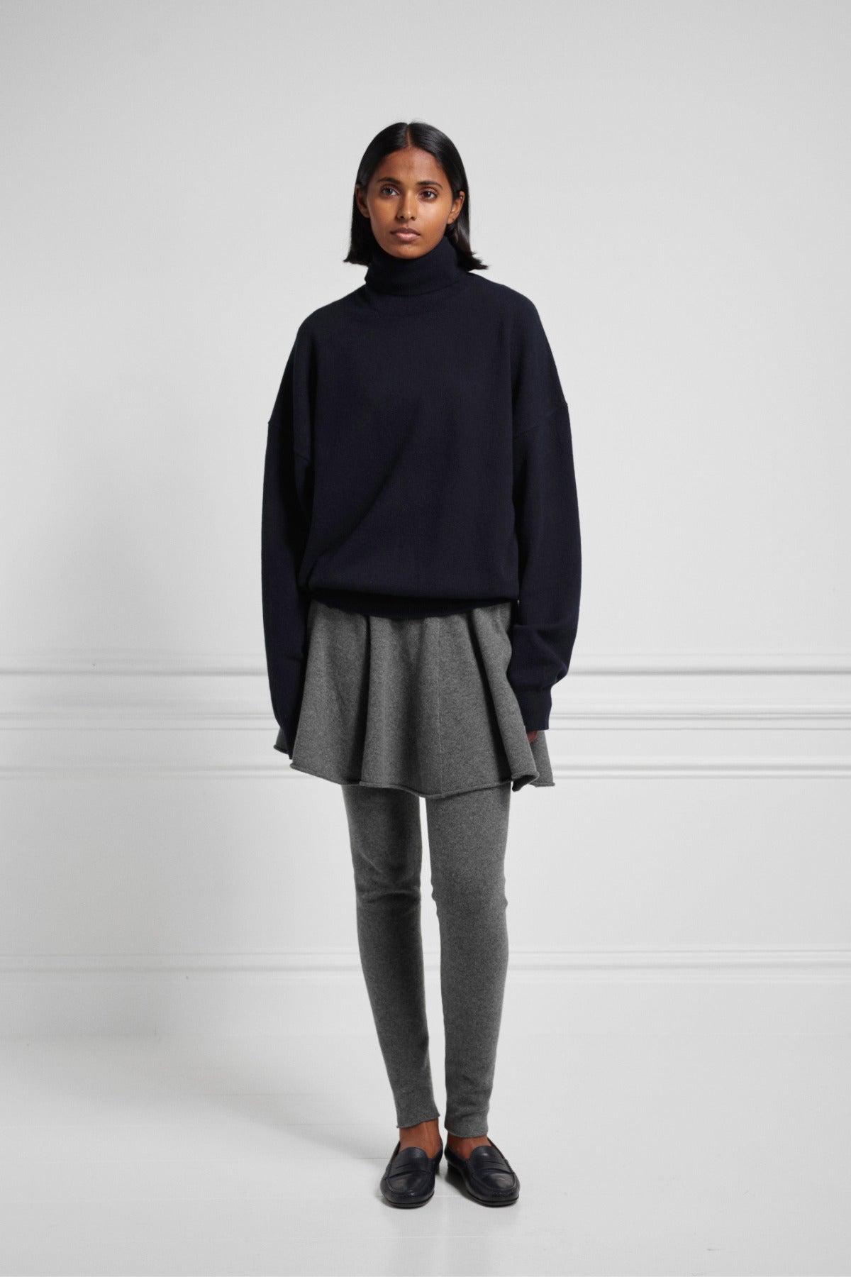 Front view of felt girl skirt on model wearing grey leggings, a navy pullover, and black loafers.