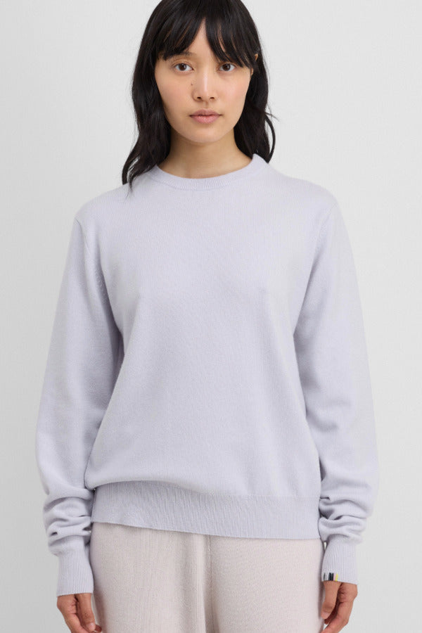 Front view of heaven be classic sweater on dark-haired model wearing white trousers, against a white background