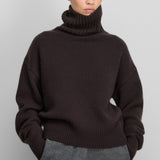 Front view of dark brown no 434 crop xtra sweater on model wearing grey pants, against a white background.