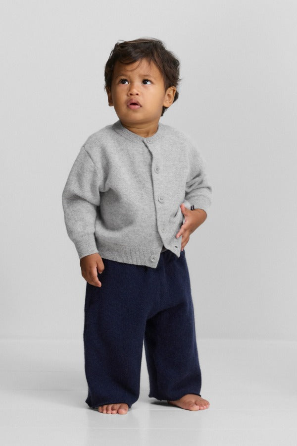 Front view of grey no 440 toddler cardigan on model wearing navy pants, against a white background.