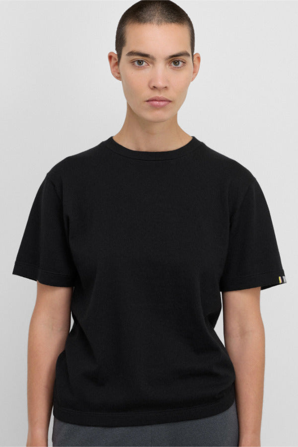 Front view of raven cuba top on dark- haired model in grey pants, against white background