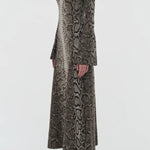 Side view of greyscale aalia dress on model wearing boots, against a white background.