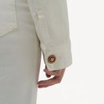 Back closeup view of white bronte jacket on model wearing white pants, against a white background.