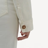 Back closeup view of white bronte jacket on model wearing white pants, against a white background.