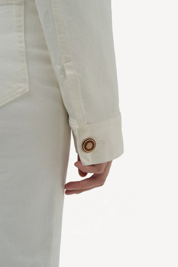 Back closeup view of white bronte jacket on model wearing white pants, against a white background.