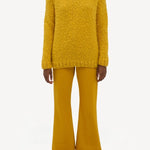 Front view of golden birch cashmere lawrence sweater on. model wearing yellow pants and sneakers, against a white background.