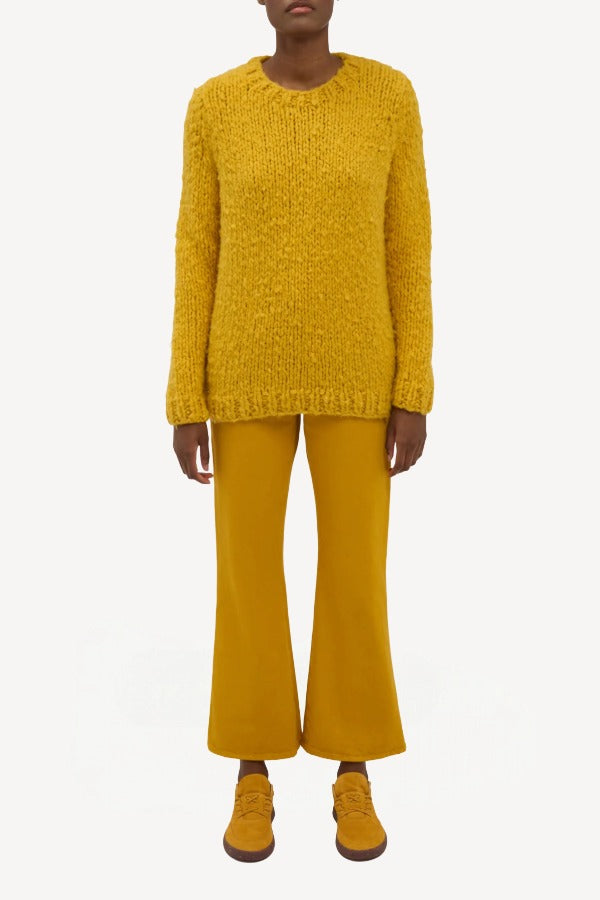 Front view of golden birch cashmere lawrence sweater on. model wearing yellow pants and sneakers, against a white background.