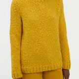 Closeup view of golden birch cashmere lawrence sweater on model wearing yellow sweater, against a white background.