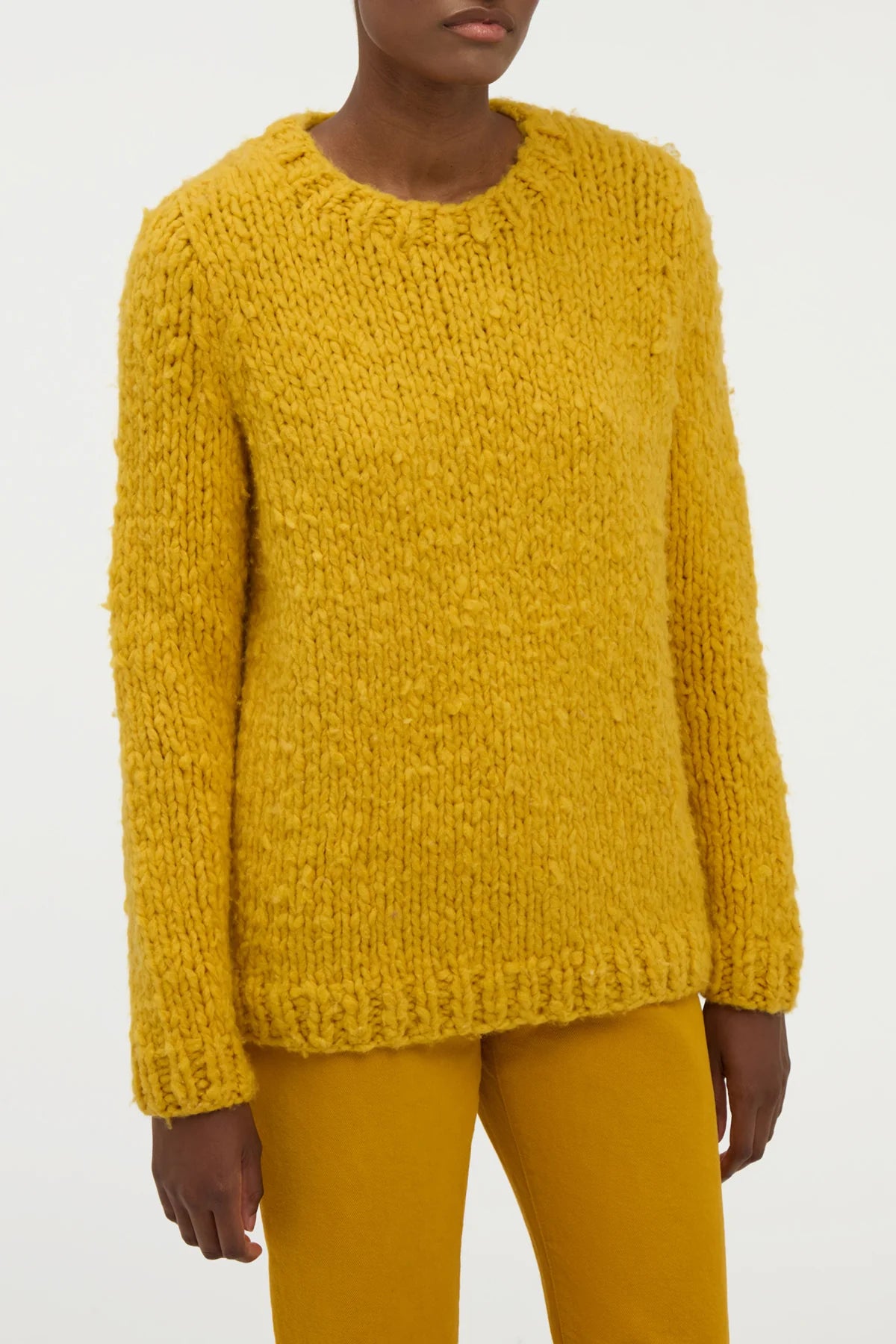 Closeup view of golden birch cashmere lawrence sweater on model wearing yellow sweater, against a white background.