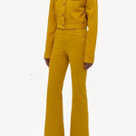 Side view of golden birch ezra bootcut jean on model wearing golden birch jacket and boots, against a white background.