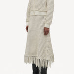 Side slanted view of white odin bomber jacket on model wearing white bennie skirt and boots, against a white background.