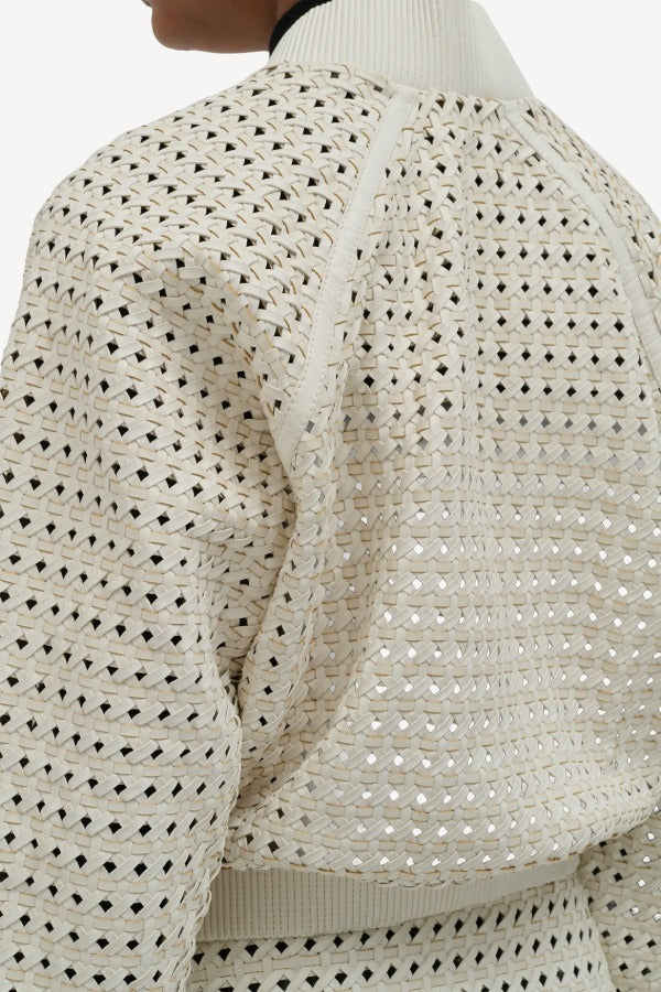 Back closeup view of white odin bomber jacket on model wearing white bennie skirt, against a white background.