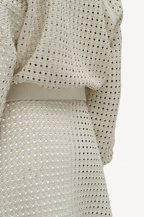 Alternate back closeup view of white odin bomber jacket on model wearing white bennie skirt, against a white background.