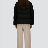 Back view of black jacket in arendelle on model wearing beige pants, against a white background.