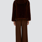 Back view of fondante knitted jacket on model wearing chocolate pants and flats, against a white background.