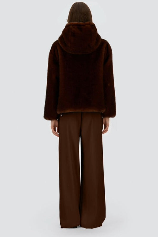 Back view of fondante knitted jacket on model wearing chocolate pants and flats, against a white background.