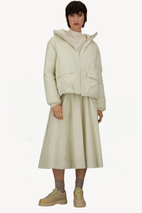 Front view of panna scuro jacket on model wearing cream skirt and sneakers, against a white background.