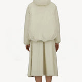 Back view of panna scuro jacket on model wearing cream skirt and sneakers, against a white background.