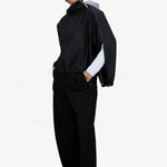 Front slanted view of black wool jacket on model wearing black pants, against a white background.